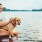 Woman holding her dog by a lake